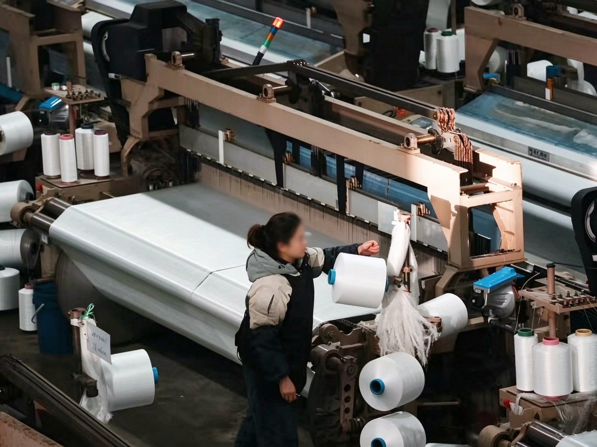 Water-jet and air-jet looms weaving stretch fabric in the Mifu Textile mill, Shengze China